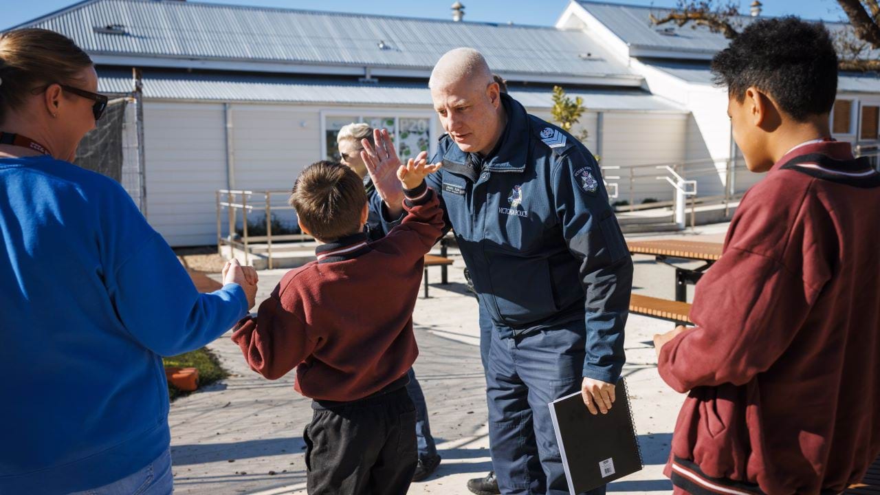 DLO in uniform giving a child in a school uniform a high-five during a primary school visit. 