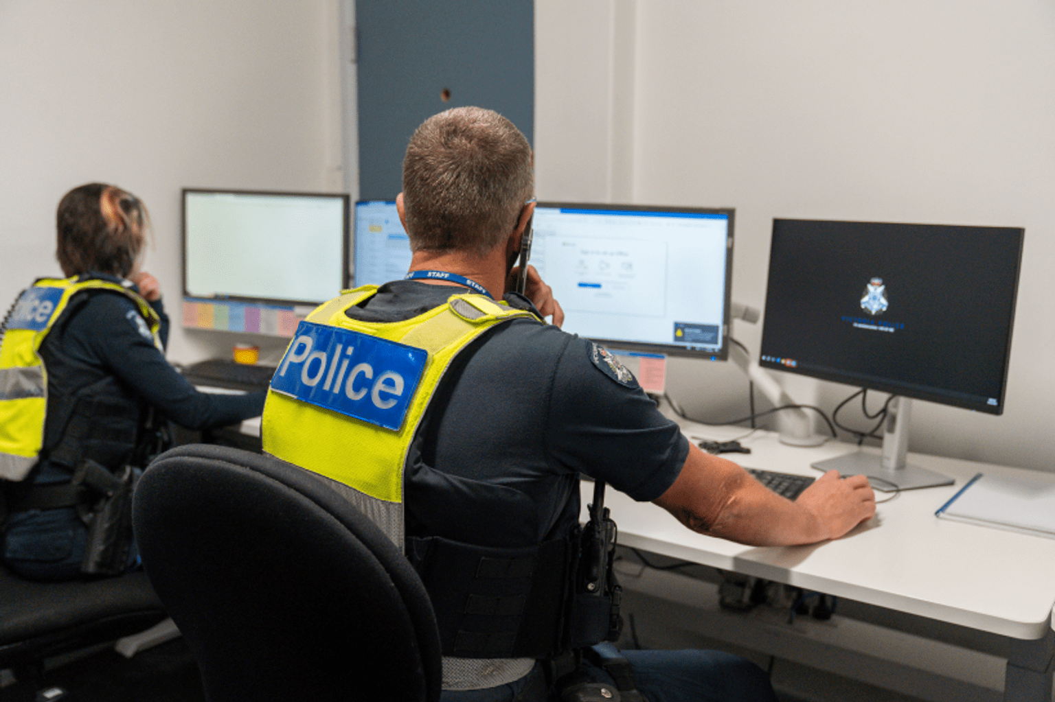 Police officers responding to phone calls and working at a computer.
