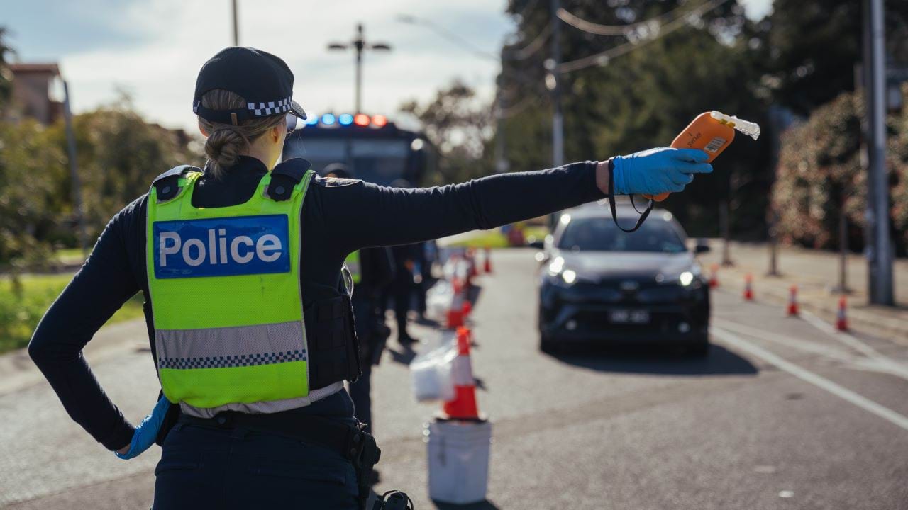 Female police officer in police uniform, on stopping a car at the side of the road at a roadside testing point. 